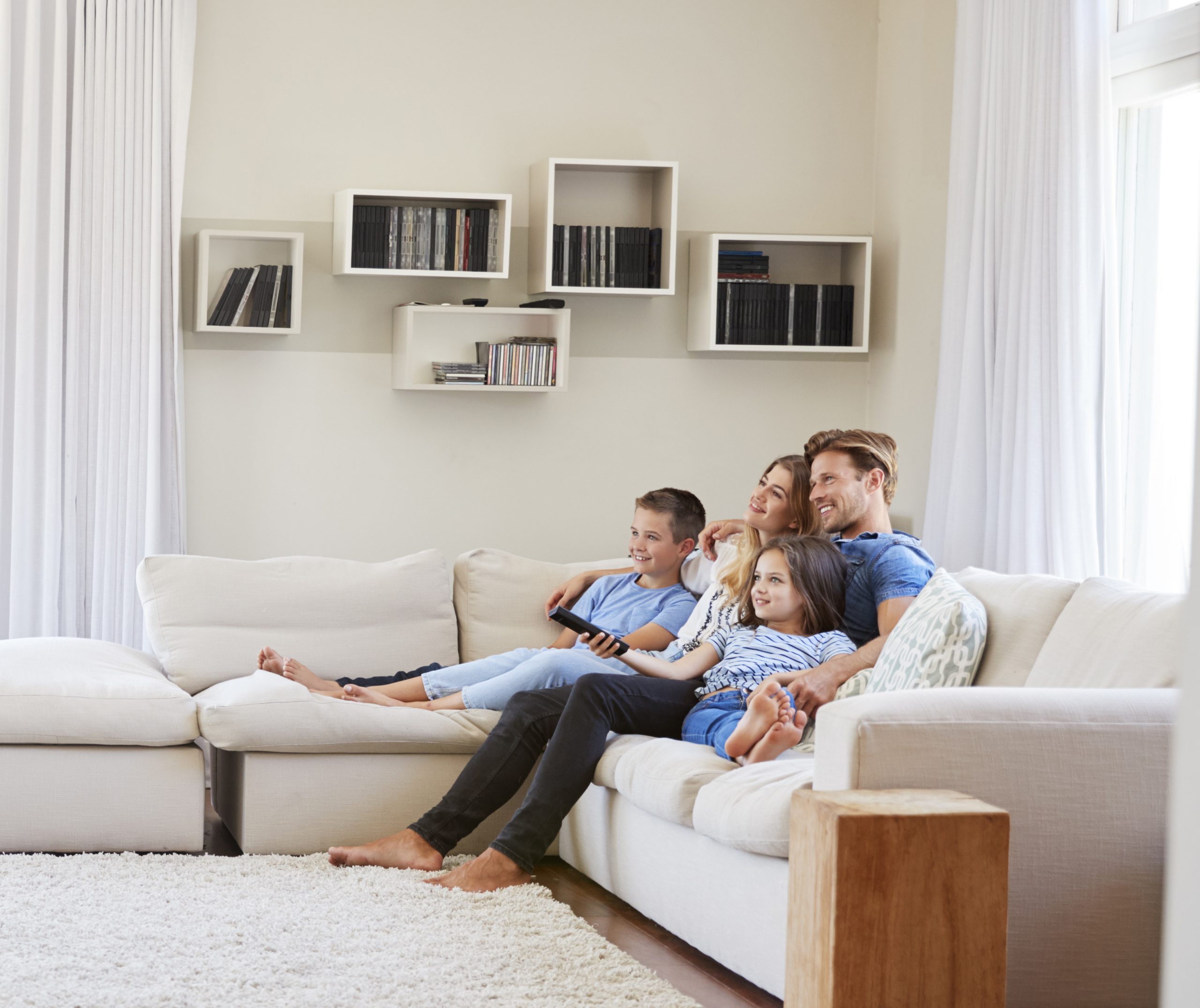 Family Sitting On Sofa At Home Watching TV Together